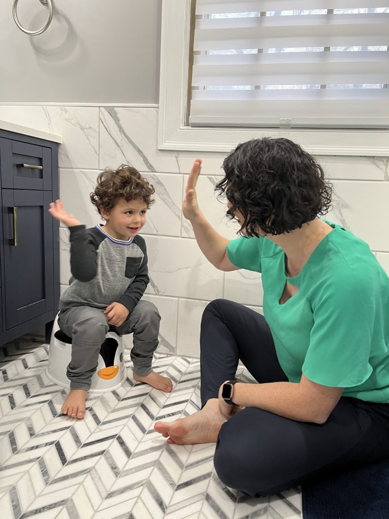 Physical Therapy can help stop bedwetting. Child high fiving adult, practicing using the potty, picture for the blog about Pediatric Bladder Physical Therapist